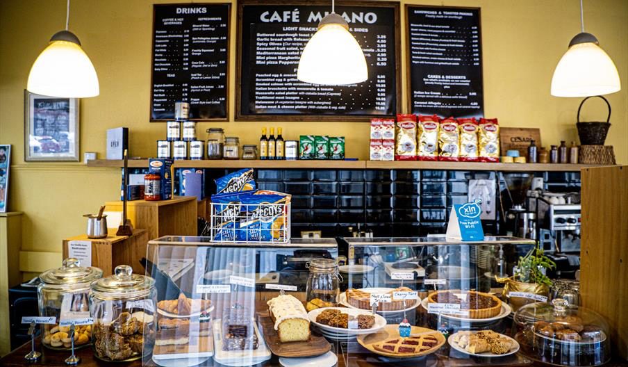 Inside Cafe Milano — the counter, cakes, and chalkboard menu